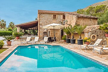 A large swimming pool in front of a stone house