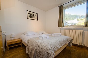 A bedroom with a bed and a window with mountains in the background