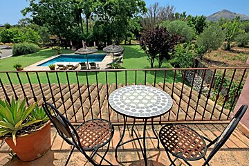 A table and chairs on a balcony overlooking a swimming pool