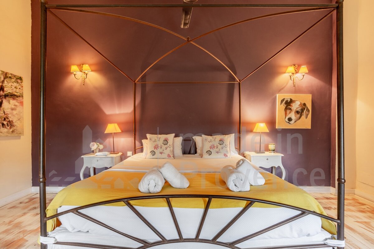 A bedroom with a canopy bed and a picture of a dog on the wall