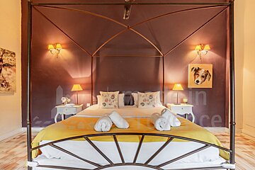 A bedroom with a canopy bed and a picture of a dog on the wall