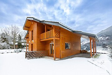 A large wooden house with mountains in the background