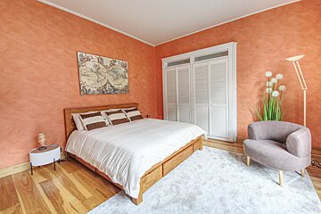 A bedroom with a large bed and a chair