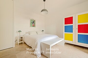 A bedroom with a bed and a colorful wardrobe made in provence by immobilier