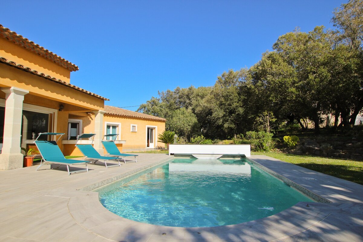 A house with a large swimming pool in front of it