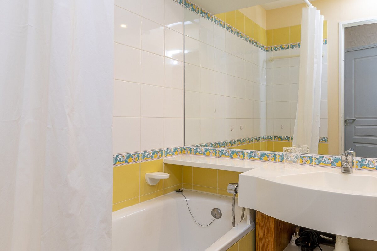 A bathroom with yellow and white tiles and a sink