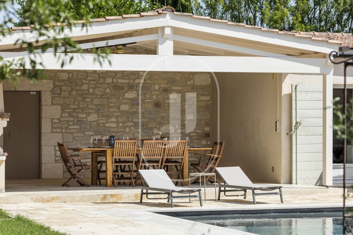 A patio with a table and chairs next to a pool