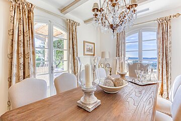 A dining room table with a chandelier and candles on it
