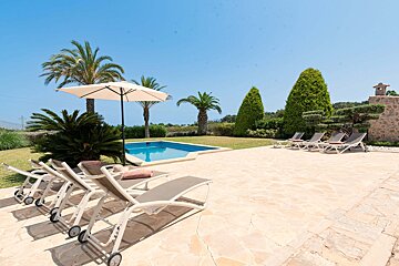 A row of lounge chairs under an umbrella next to a pool