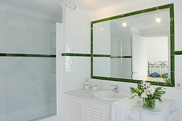 A bathroom with green tiles and a large mirror
