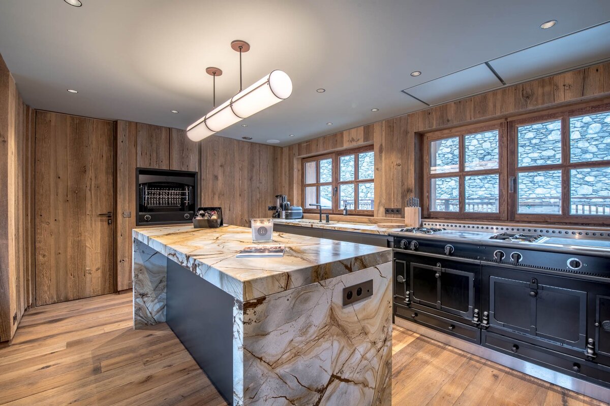 A kitchen with a marble counter top and wooden cabinets
