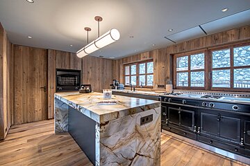 A kitchen with a marble counter top and wooden cabinets