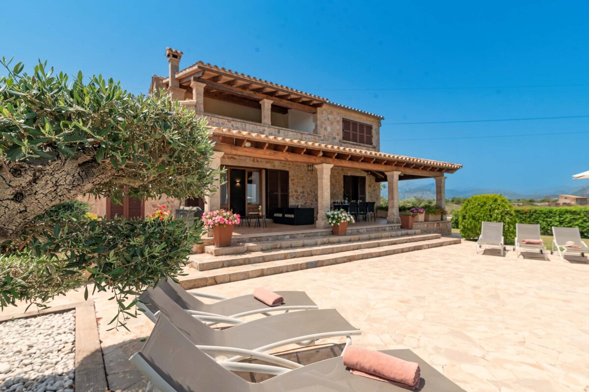 A large stone house with a patio and chairs in front of it