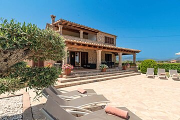 A large stone house with a patio and chairs in front of it