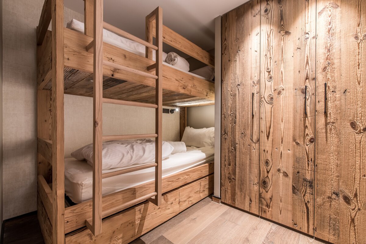 A wooden bunk bed with a ladder leading up to it
