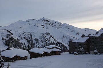 A snowy mountain with a building in the foreground