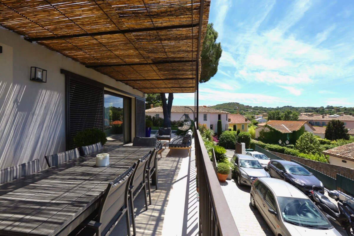 A balcony with a table and chairs under a canopy