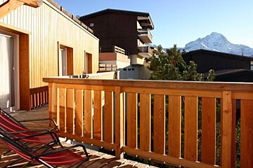 A wooden balcony with chairs and a mountain in the background