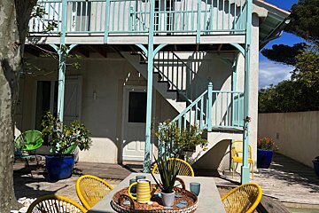 A table with a pitcher on it sits in front of a house