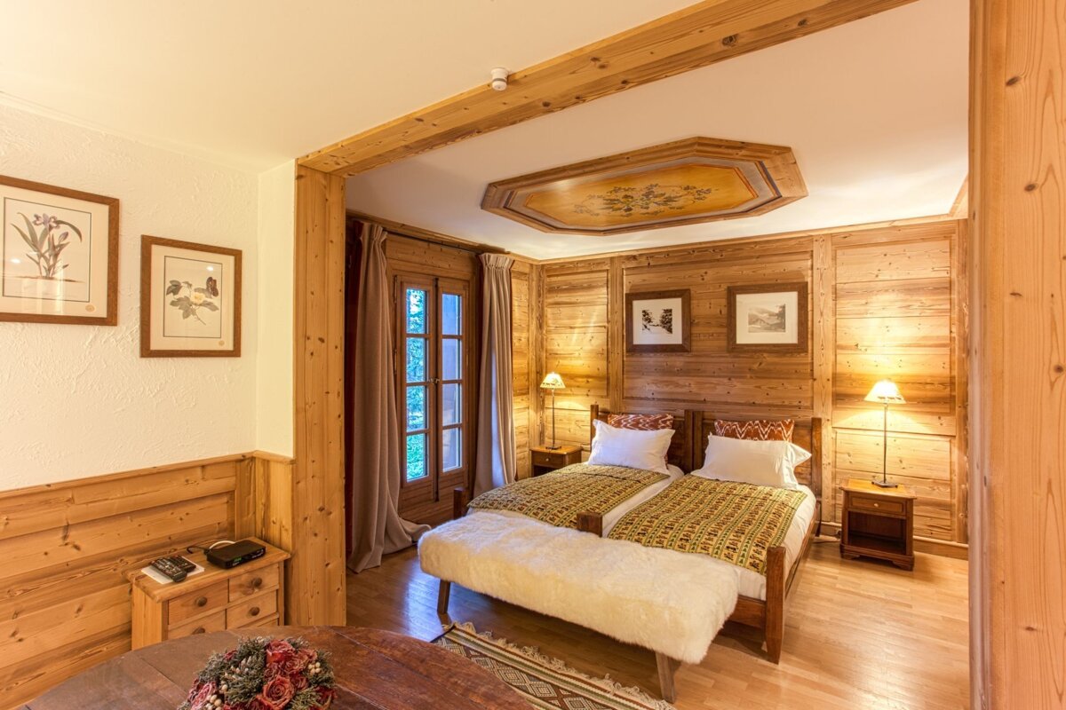 A bedroom with two beds and a painting on the ceiling
