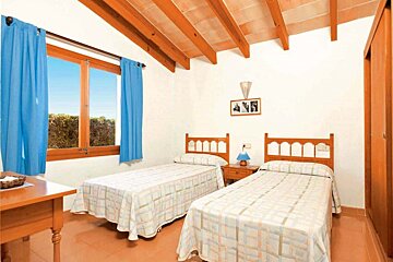 A bedroom with two beds and blue curtains