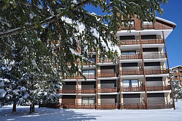 A building with a lot of balconies is covered in snow