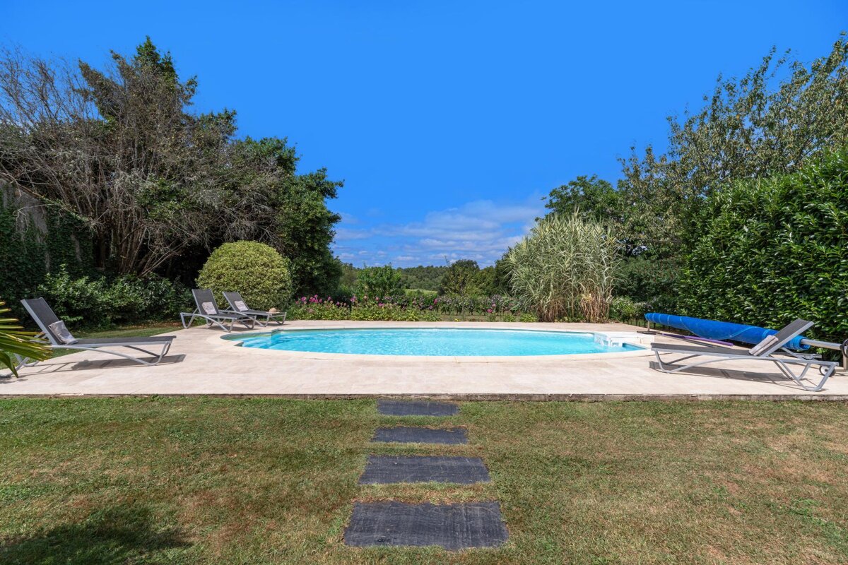 A swimming pool surrounded by lawn chairs and trees