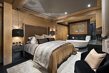 A bedroom with a large bed and a bathtub