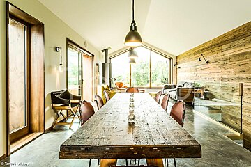 A dining room with a long wooden table and chairs