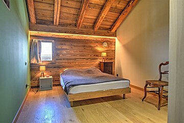 A bedroom with a wooden ceiling and a bed
