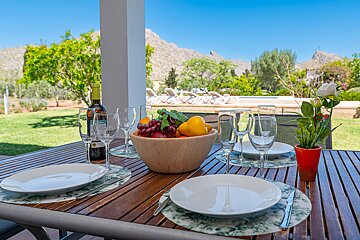 A bowl of fruit sits on a table next to a bottle of wine