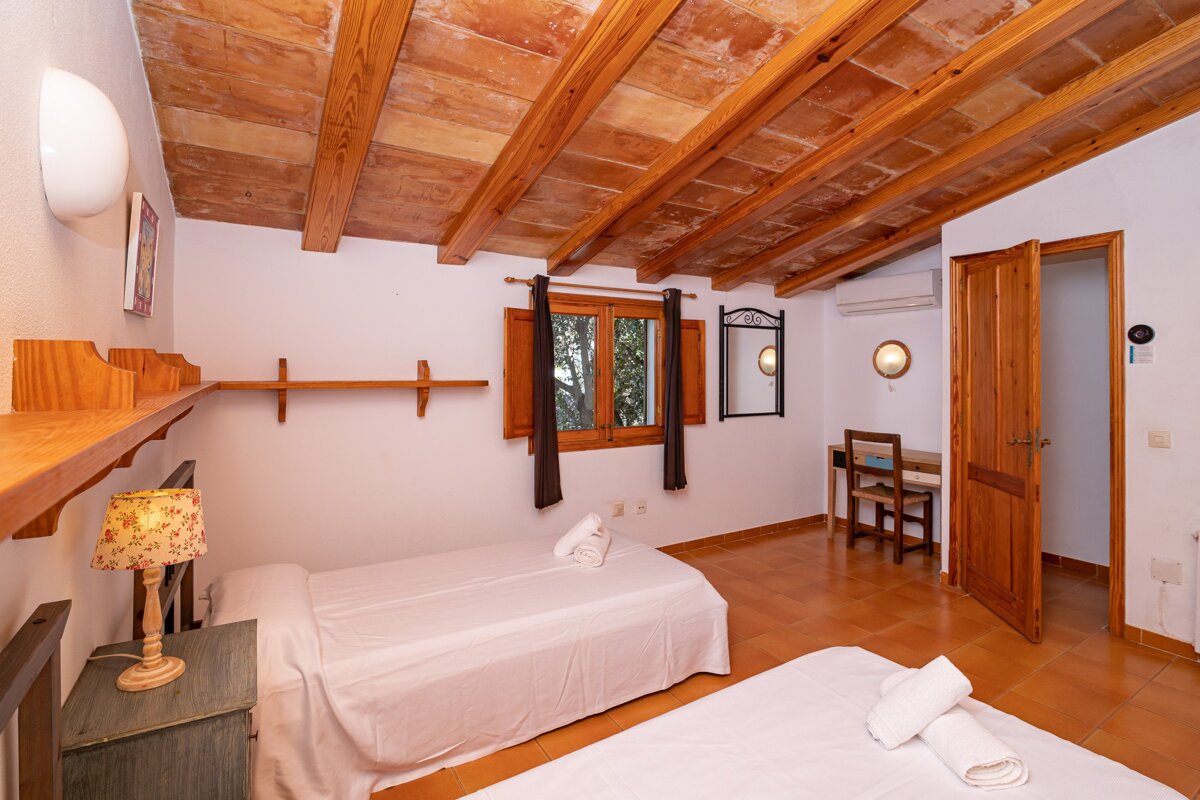 A bedroom with two beds and a lamp on the nightstand