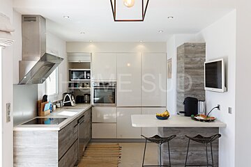 A kitchen with white cabinets and stools and the word home sud on the wall