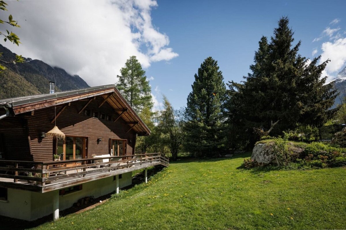 A wooden house with a balcony and mountains in the background