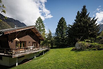 A wooden house with a balcony and mountains in the background