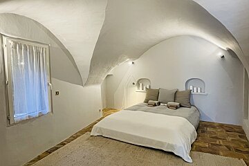 A bedroom with arched ceilings and a bed
