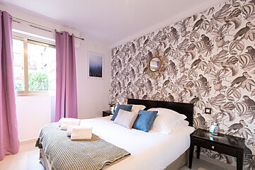 A bedroom with birds on the wall and purple curtains