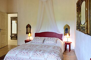 A bedroom with a canopy bed and two mirrors