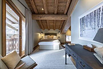 A bedroom with a picture of trees on the wall above the bed