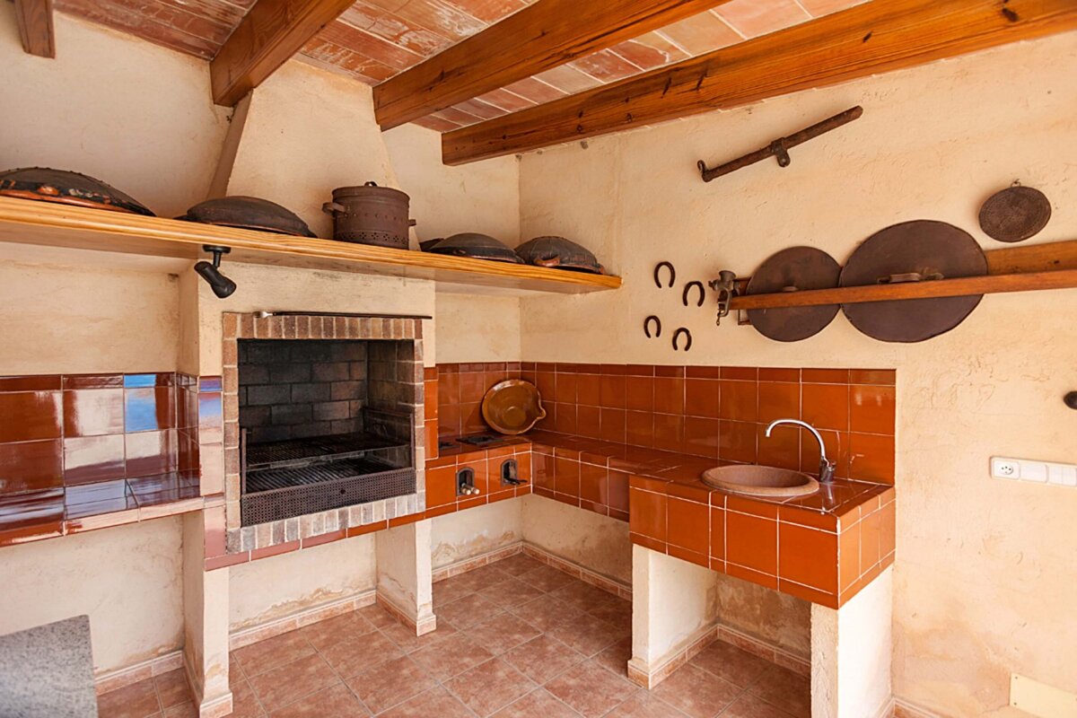 A kitchen with pots and pans on a shelf and horseshoes on the wall