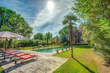A large swimming pool surrounded by lawn chairs and umbrellas