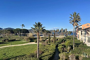 A view of a park with palm trees and mountains in the background