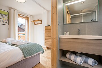 A bathroom with a sink and mirror next to a bedroom