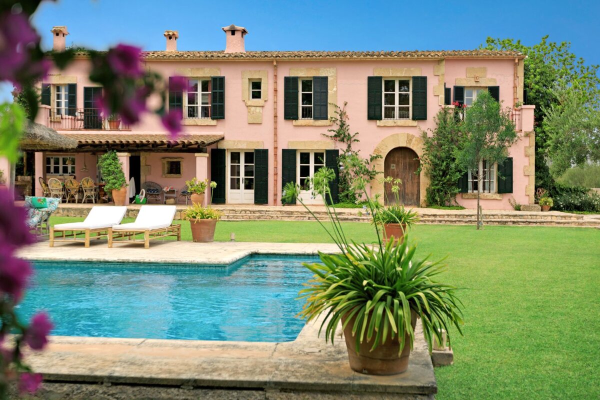 A large pink house with a swimming pool in front of it