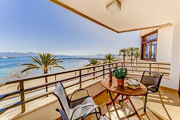 A balcony with a table and chairs overlooking the ocean