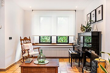 A living room with a rocking chair and a piano