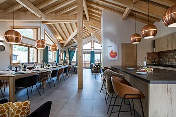 A dining room with a large table and chairs and a copper light fixture
