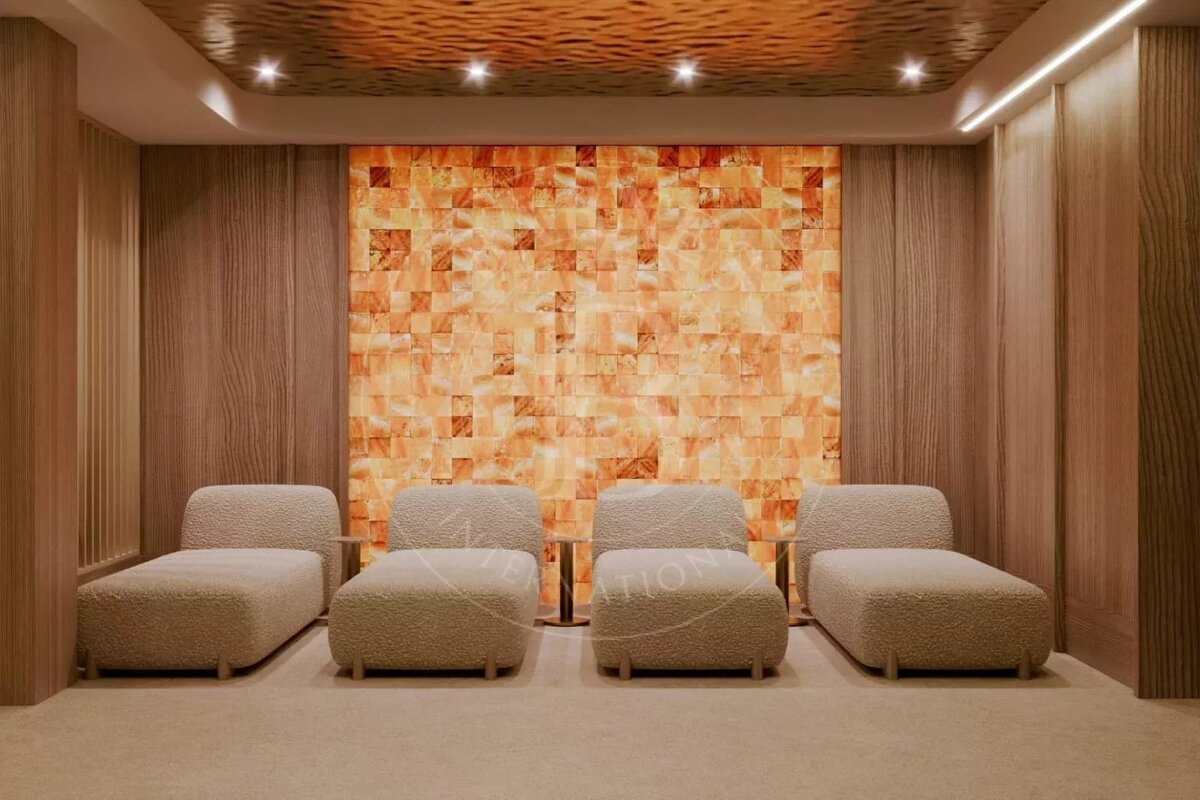 A tranquil spa room with a glowing Himalayan salt block wall, four beige lounge chairs, warm wooden paneling, and a textured ceiling.