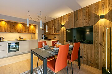 A kitchen with a table and chairs and a flat screen tv