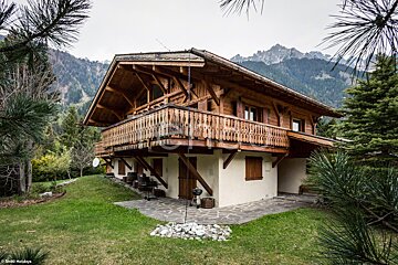 A house with a balcony and mountains in the background
